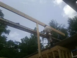 Carpenter setting a ridge beam over a new addition frame — Ice Dam Removal by Roofing Brothers in Beltrami