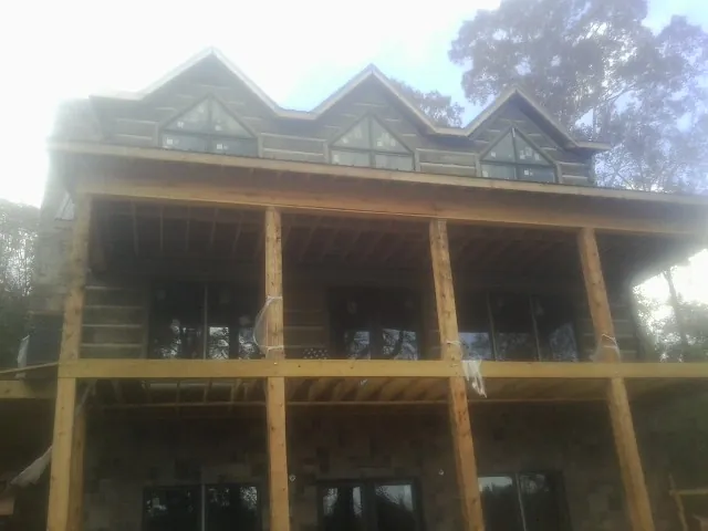 Dormers and porch framing on a large log home under construction — Roof Coating work by our crew in Beltrami