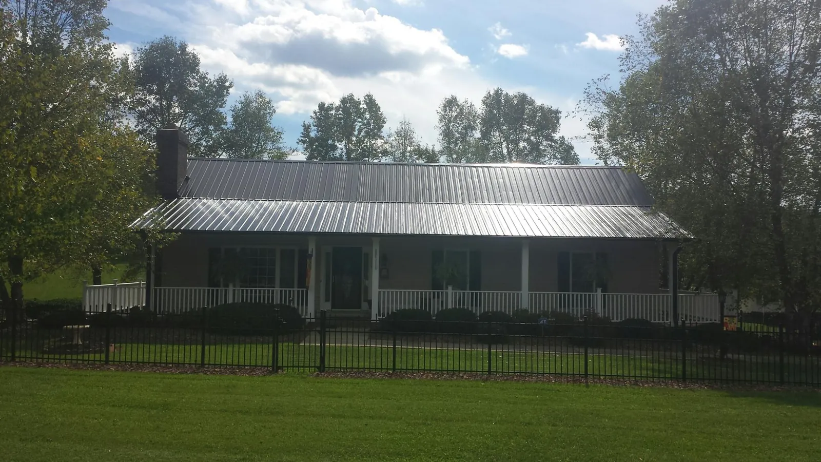 Gray metal roof on a brick ranch with a full width front porch — Gutter Guard Installation work by our crew in Beltrami
