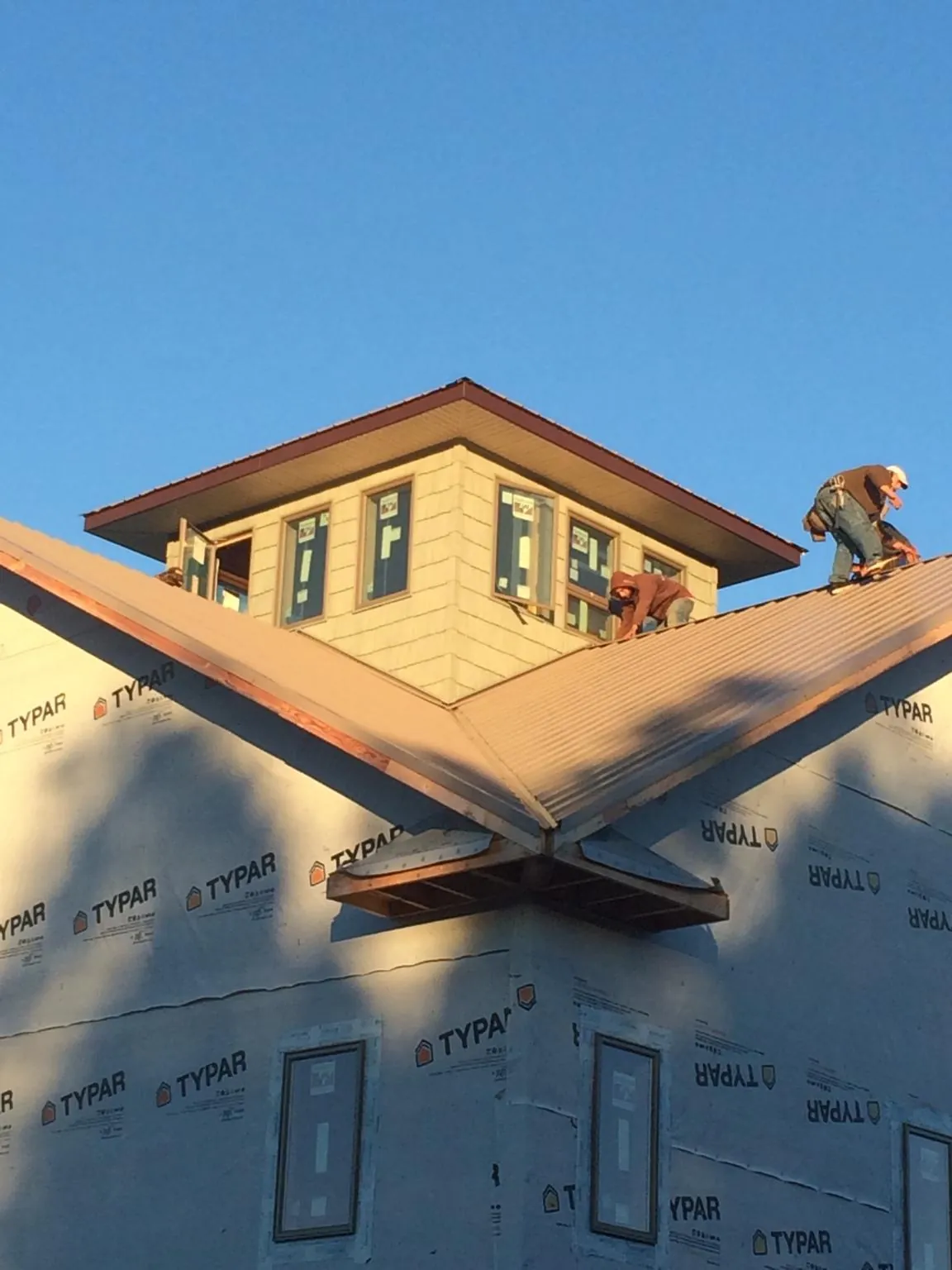 Roofers working around a rooftop cupola on a new metal roof at sunset — Roof Waterproofing in Beltrami by Roofing Brothers